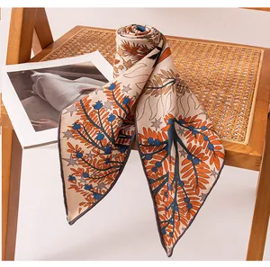 Macro view of botanical print silk wool triangle scarf draped on a rattan chair