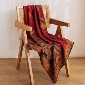Elegant mulberry silk scarf featuring a traditional red pattern draped over a chair.