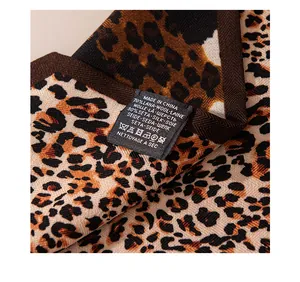 Close-up of care label on leopard print silk wool scarf showing material composition