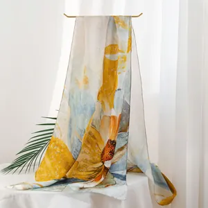 Elegant mulberry silk scarf featuring a large yellow and blue floral print on white background