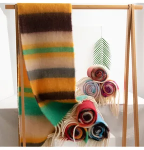 Close-up of colorful mohair scarves with tassels displayed on a wooden rack.