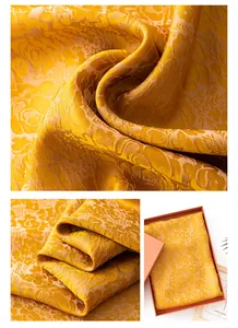 Makroaufnahme eines luxuriösen goldenen Seidenschals mit elegantem floralem Jacquard-Muster.
