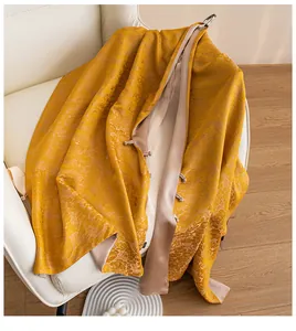 Detaillierte Nahaufnahme eines luxuriösen goldenen Seidenschals mit floralem Jacquard-Muster.