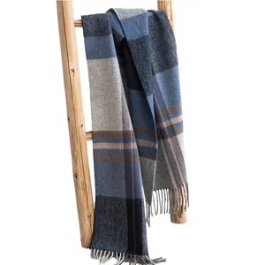 Elegant plaid woolen scarf with fringe tassels draped naturally on a rustic wooden ladder