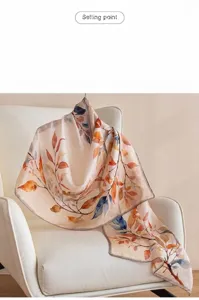 Macro detail of a luxury silk scarf with autumn leaf patterns draped on a white chair