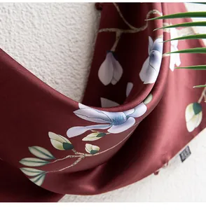 Detailansicht eines luxuriösen ziegelroten Seidenschals mit elegantem Magnolienblütendruck