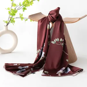 Eleganter seidenschal in ziegelrot mit magnolien-print auf einem display-ständer
