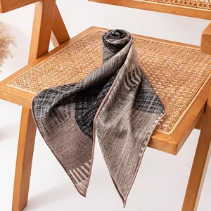 Elegant silk and wool blend triangular scarf with abstract striped patterns on a rattan chair.