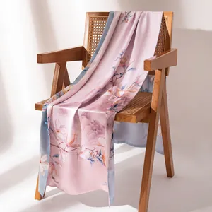 Elegant double-layered silk scarf with pink magnolia floral print draped on a wooden chair