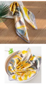 Close-up detail of luxury 100% mulberry silk scarf with vibrant yellow floral patterns