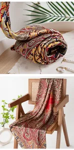 Elegant mulberry silk scarf with classic paisley pattern draped over a wooden chair.