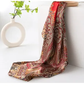 Close-up detail of luxurious red silk scarf with classic paisley print on white stand