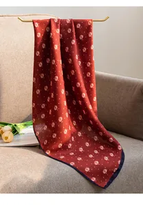 Close-up detail of a red cotton linen square scarf with elegant white leaf print patterns