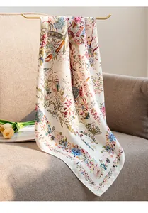Detailed macro view of a beige floral silk-like scarf draped elegantly on a sofa.