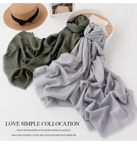 Detail showing the soft texture and fringed edges of olive and gray wool scarves