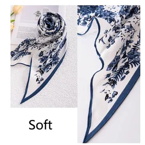Elegant blue floral print triangular silk scarf for women displayed on a white surface