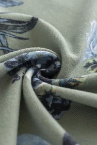 Close-up of sage green synthetic cashmere scarf with blue rose floral print details