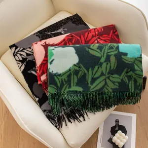 Three elegant printed imitation cashmere scarves with tassels stacked on a white chair