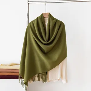 Detailed macro shot of a soft olive green cashmere-like scarf featuring elegant tassels