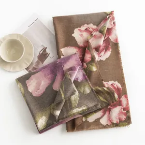 Dettaglio di una morbida sciarpa in finto cashmere con stampa a fiori di ibisco e frange