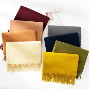 Variety of solid color faux cashmere scarves with tassels displayed on a clean background
