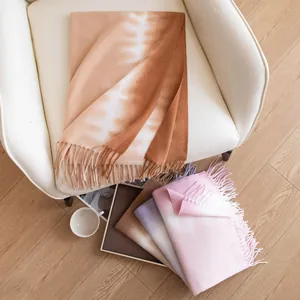 Soft cashmere-feel scarves with tie-dye patterns and tassels in a cozy home setting