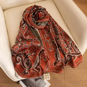 Eleganter Seiden-Wollschal mit rotem Paisley-Muster auf einem weißen Stuhl für Lifestyle.