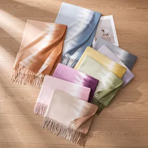 Artistic top view of multi-colored tie-dye fringe scarves displayed on a warm wooden floor