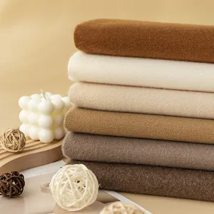 Close-up of a stack of soft winter scarves in neutral earthy tones with cozy props.