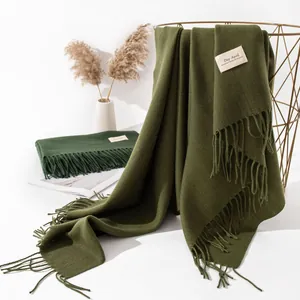 Close-up of deep green faux cashmere scarf with elegant long fringe detail.
