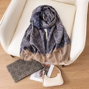 Elegant blue floral cashmere ring shawl draped on a white chair in a cozy interior.
