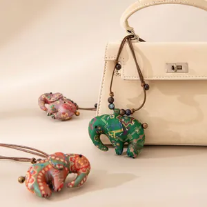 Pendentif éléphant en soie Xiangyunsha fait main sur un sac beige élégant