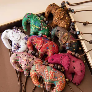Vue détaillée de pendentifs d'éléphants en soie faits main aux motifs ethniques variés