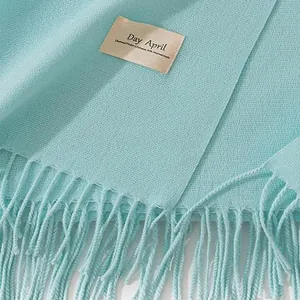 Detail of a light blue cashmere-like scarf showing soft texture and Day April brand tag