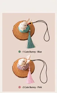 Handmade silk rabbit charms with long tassels in blue and pink displayed on wood slices.