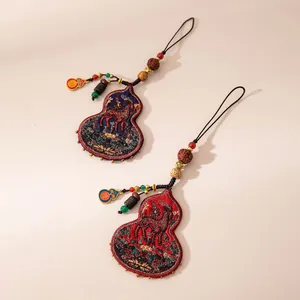 Detailed macro view of two handmade silk embroidered gourd horse charms with colorful beads