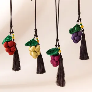 Detail view of handmade silk grape pendants with decorative tassels and leaves