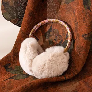 Close-up detail of cozy beige plush winter earmuffs featuring a vintage floral headband.