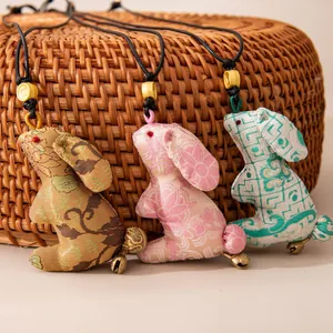 Handmade silk rabbit pendants with bells, showcasing intricate patterns and textures.