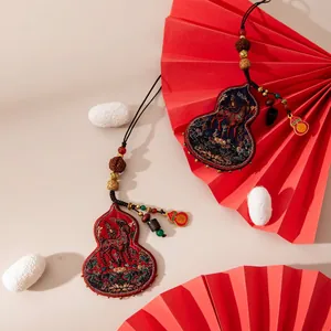 Detail of handmade silk gourd pendant with exquisite horse embroidery and bead accents.