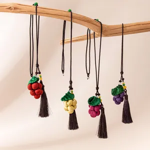 Exquisite handmade silk grape pendants in multiple colors hanging on a rustic branch with tassels