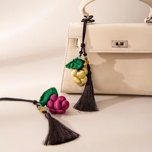 Detailed macro shot of handmade silk grape pendants with tassels on a white bag