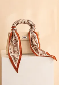 Detalle de un pañuelo de seda de morera en el asa de un bolso beige