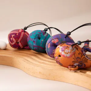 Pendentifs baleine en soie faits main aux motifs traditionnels sur un plateau en bois ondulé