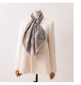 Détail d'une écharpe élégante en soie et laine avec motif cachemire sur un blazer blanc.