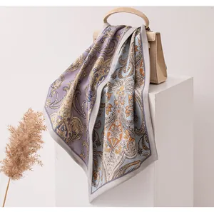 Détail d'une écharpe en soie et laine à motif paisley drapée sur un sac à main chic.