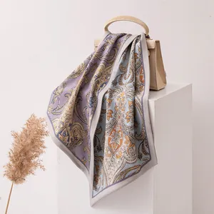 Élégant foulard en soie et laine à motif paisley drapé sur un sac à main beige