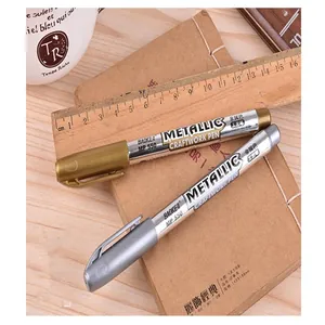 Close-up of gold and silver metallic craftwork paint pens on a vintage notebook