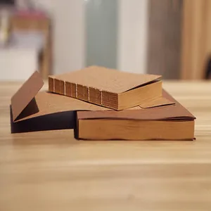 Close-up of retro kraft paper sketchbooks with exposed white stitching on a wood surface.