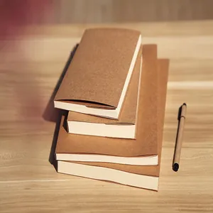 Close-up of vintage Kraft paper sketchbooks and a matching pen on a wooden desk